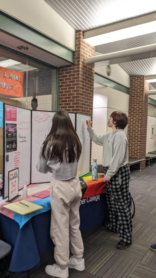 Students are write how they can be allies of LGBTQ+ people and why keeping the silence is important to them on National Day of Silence at a table set up by Pride Club next to the bookstore on April 7, 2022. (Photo by Ari McKellin.)
