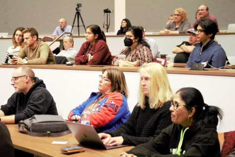 audience listen to candidates at political forum. 