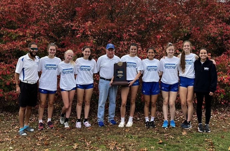 The women of the Harper cross country team smile alongside coach Jim Macnider and Assistant Coach John Majerus on November 5, 2022, at Stanley Park in Westfield, MA. (Photo courtesy of Brianna Ruiz)
