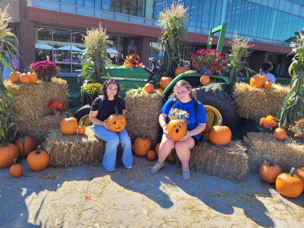 Two students and their jack olanterns pose for a photo at Fall Fest, with a special guest appearance from John Deere. (Photo by Cole Altmayer)