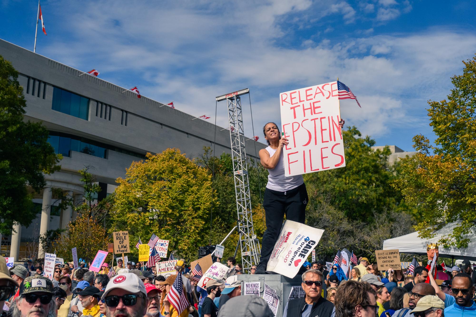 A photo of a woman holding a sign that reads, "RELEASE THE EPSTEIN FILES" at a No Kings Day protest. (Photo Courtesy of Wikimedia Commons)
